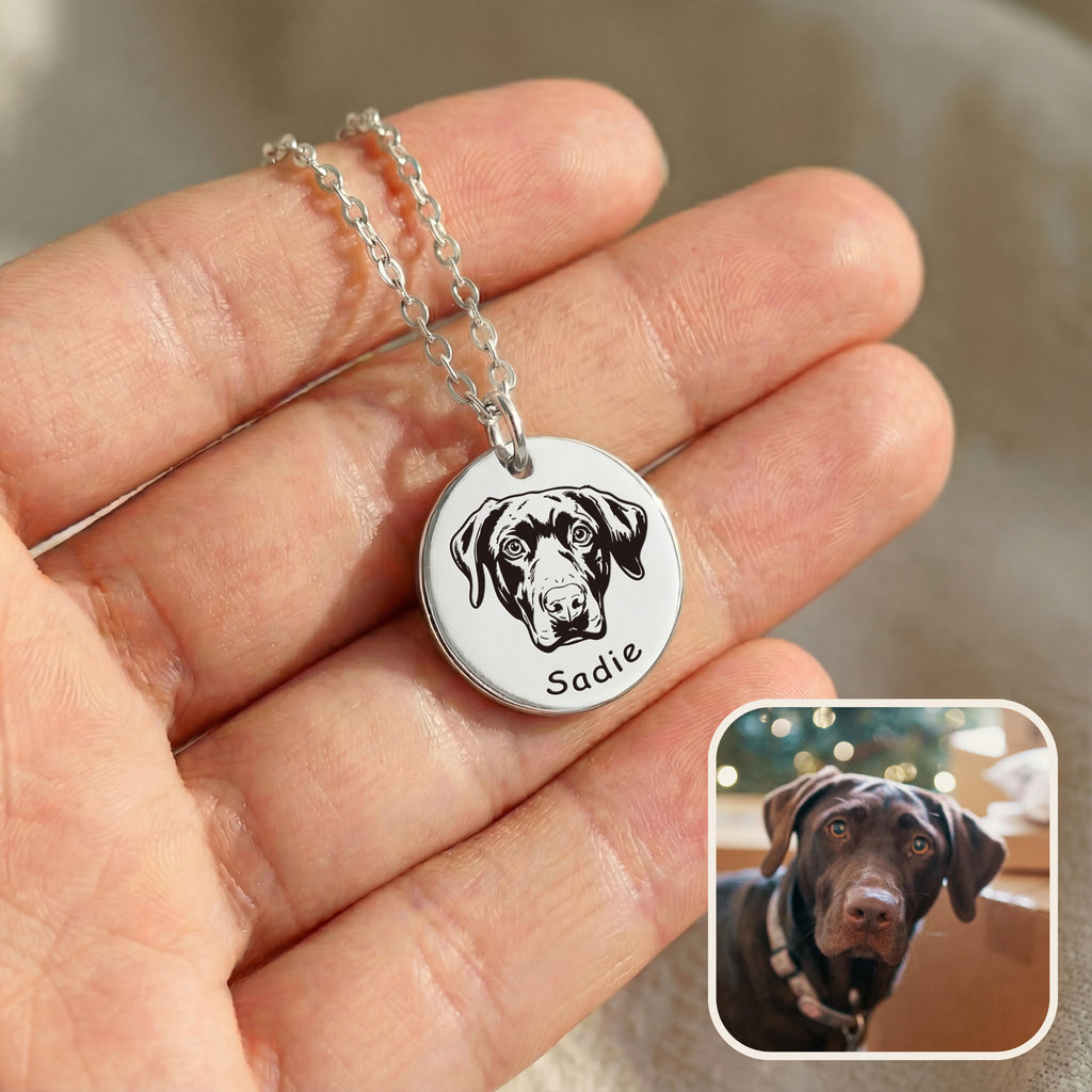 Hand holding silver pet face necklace with hand-drawn dog portrait engraving and inset photo