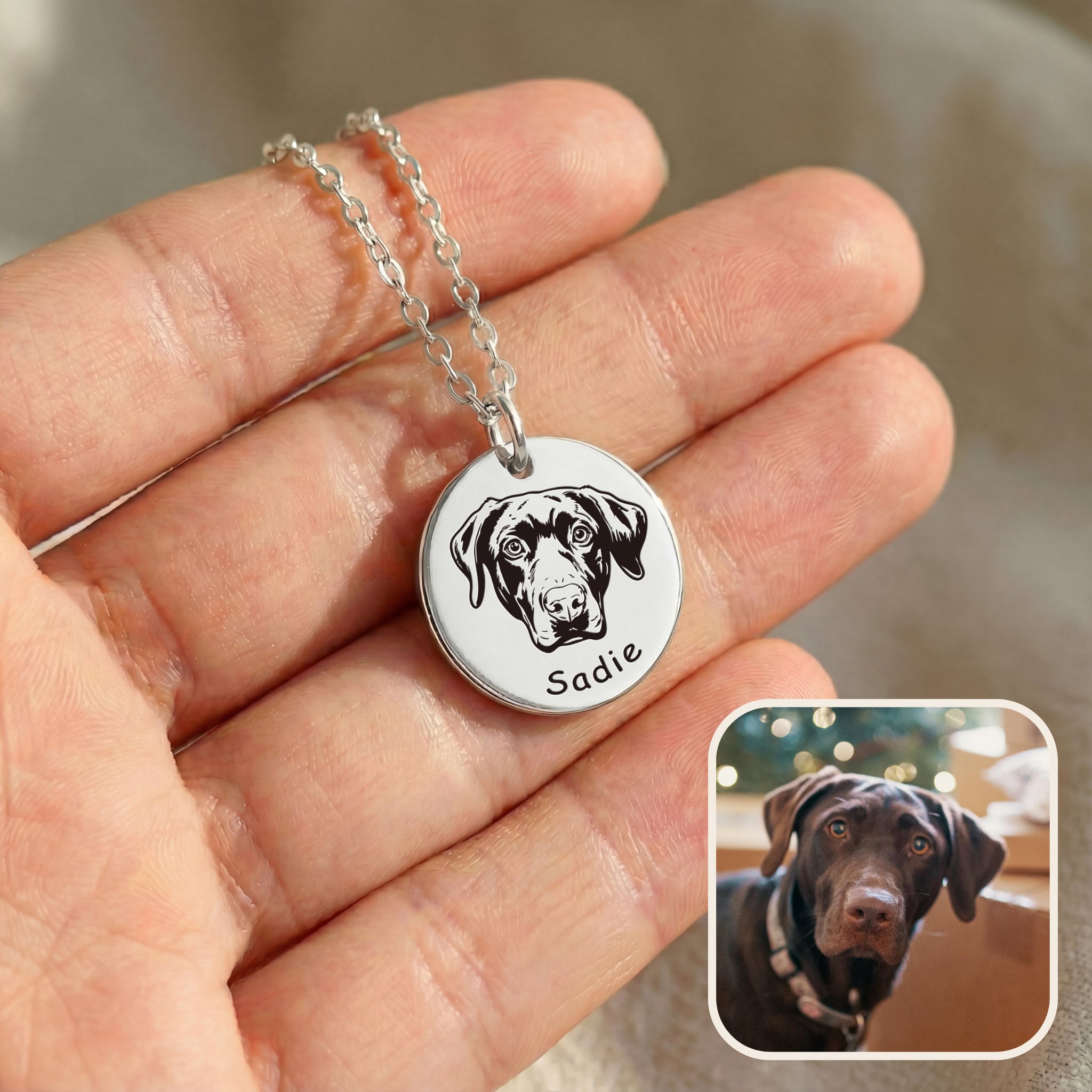 Hand holding silver pet face necklace with hand-drawn dog portrait engraving and inset photo