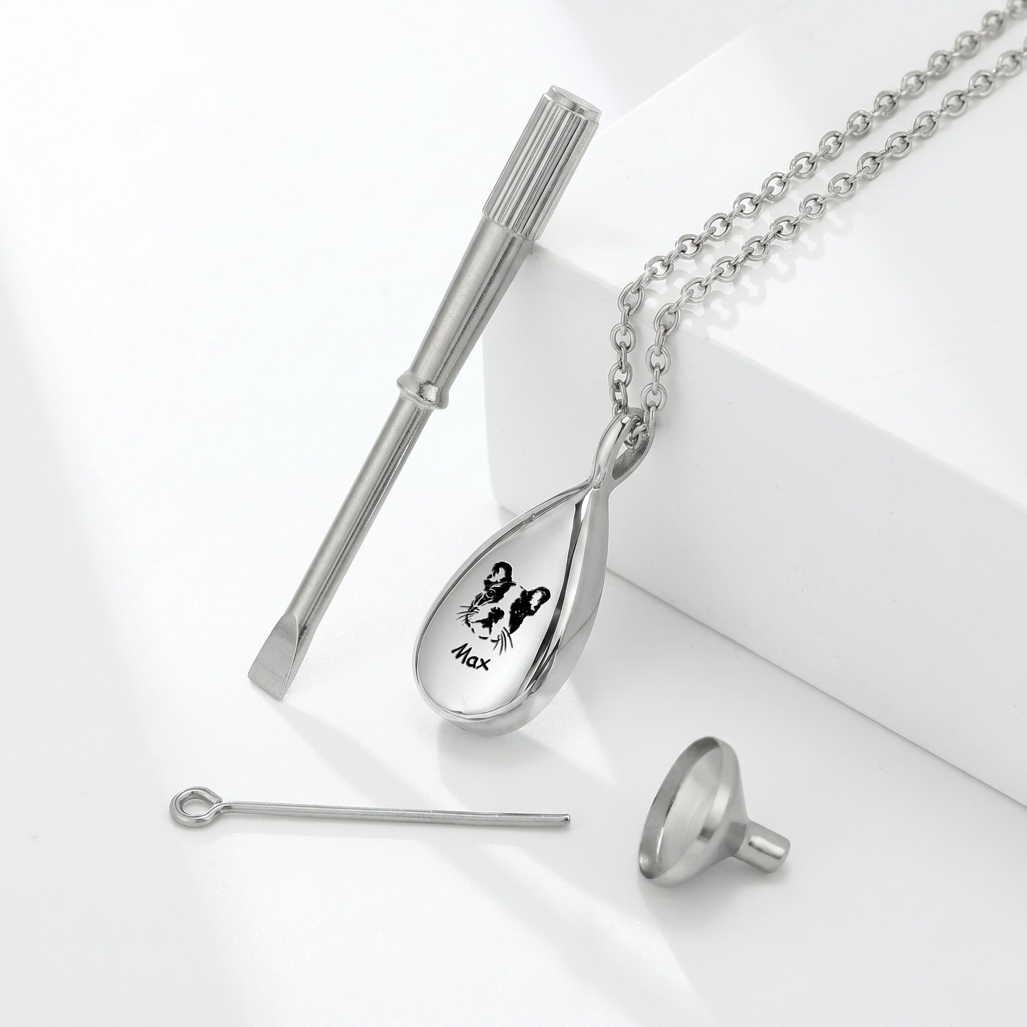 Silver teardrop pet photo urn necklace with dog portrait engraving, styled product shot