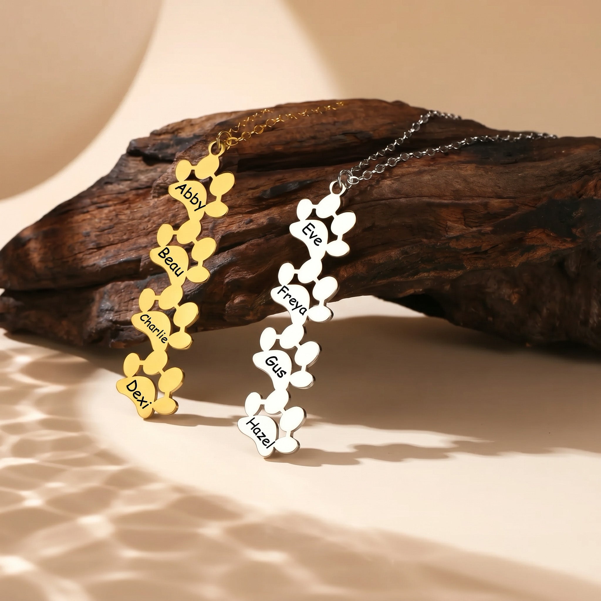 Four paw print pendants in gold and silver on natural driftwood