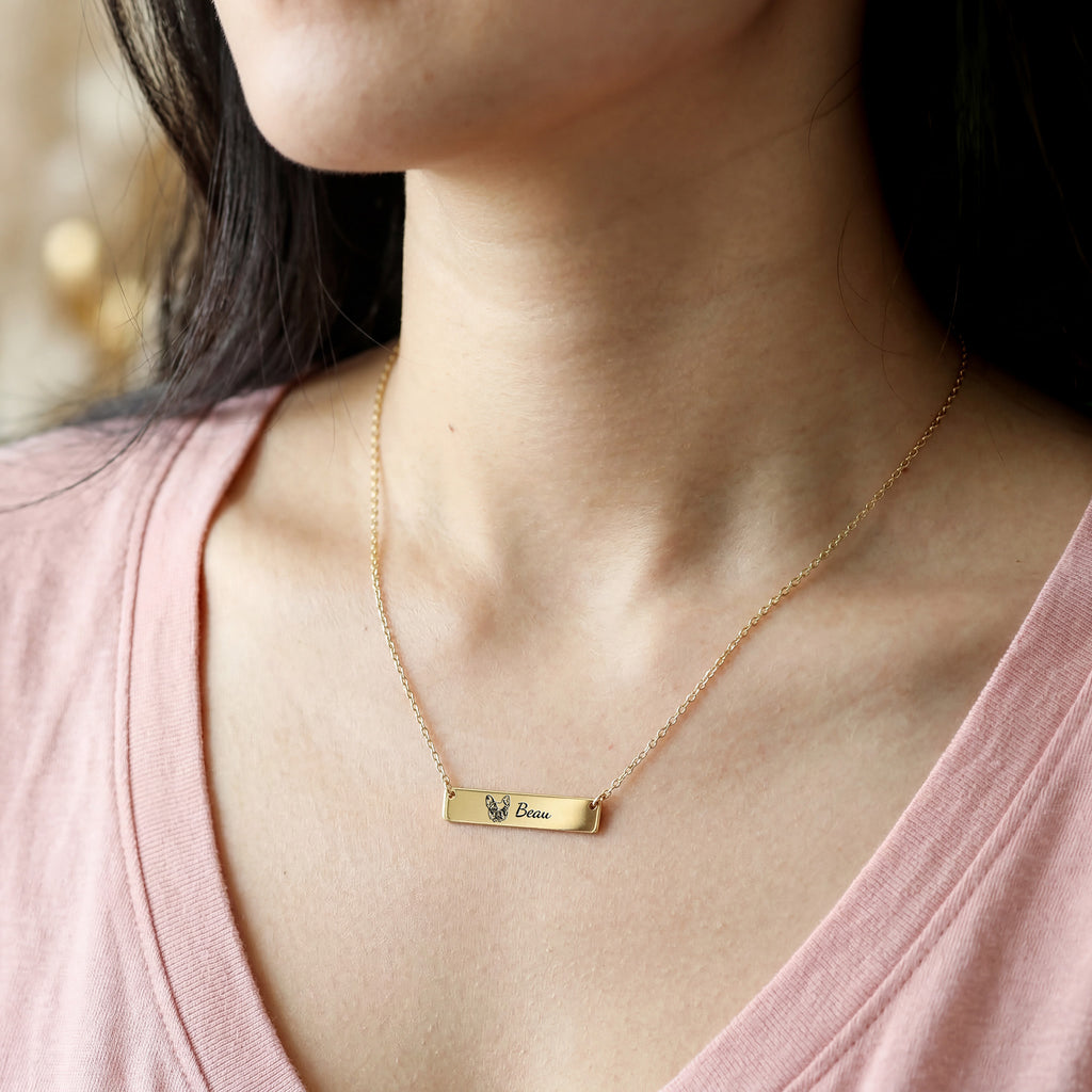 Woman wearing gold pet portrait bar necklace with engraved French Bulldog portrait and name Beau