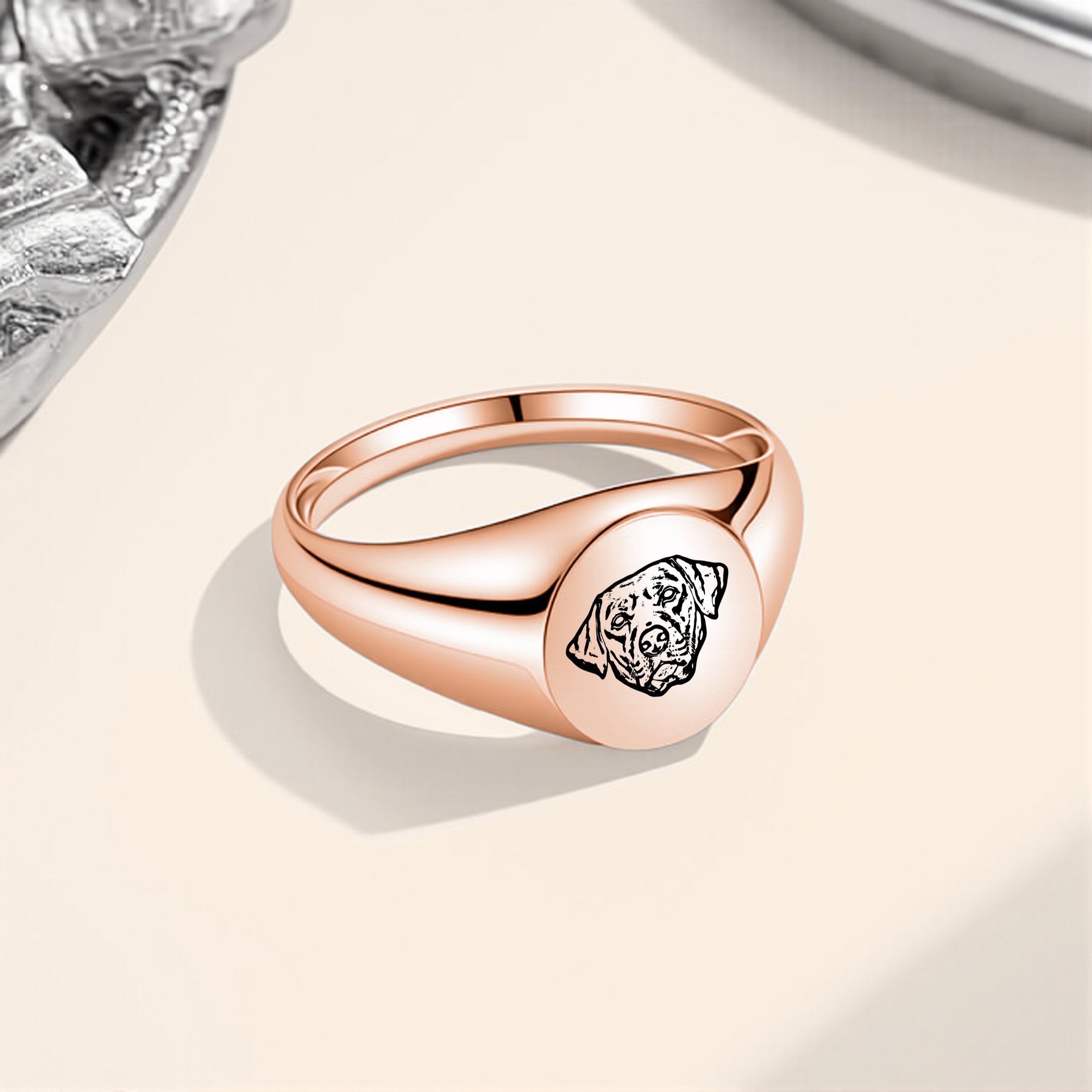 Rose gold pet portrait signet ring with laser-engraved portrait on a beige surface
