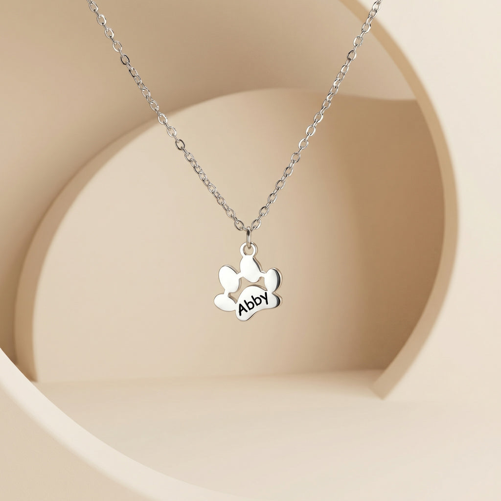 Single silver paw print pendant with engraved name on cream display