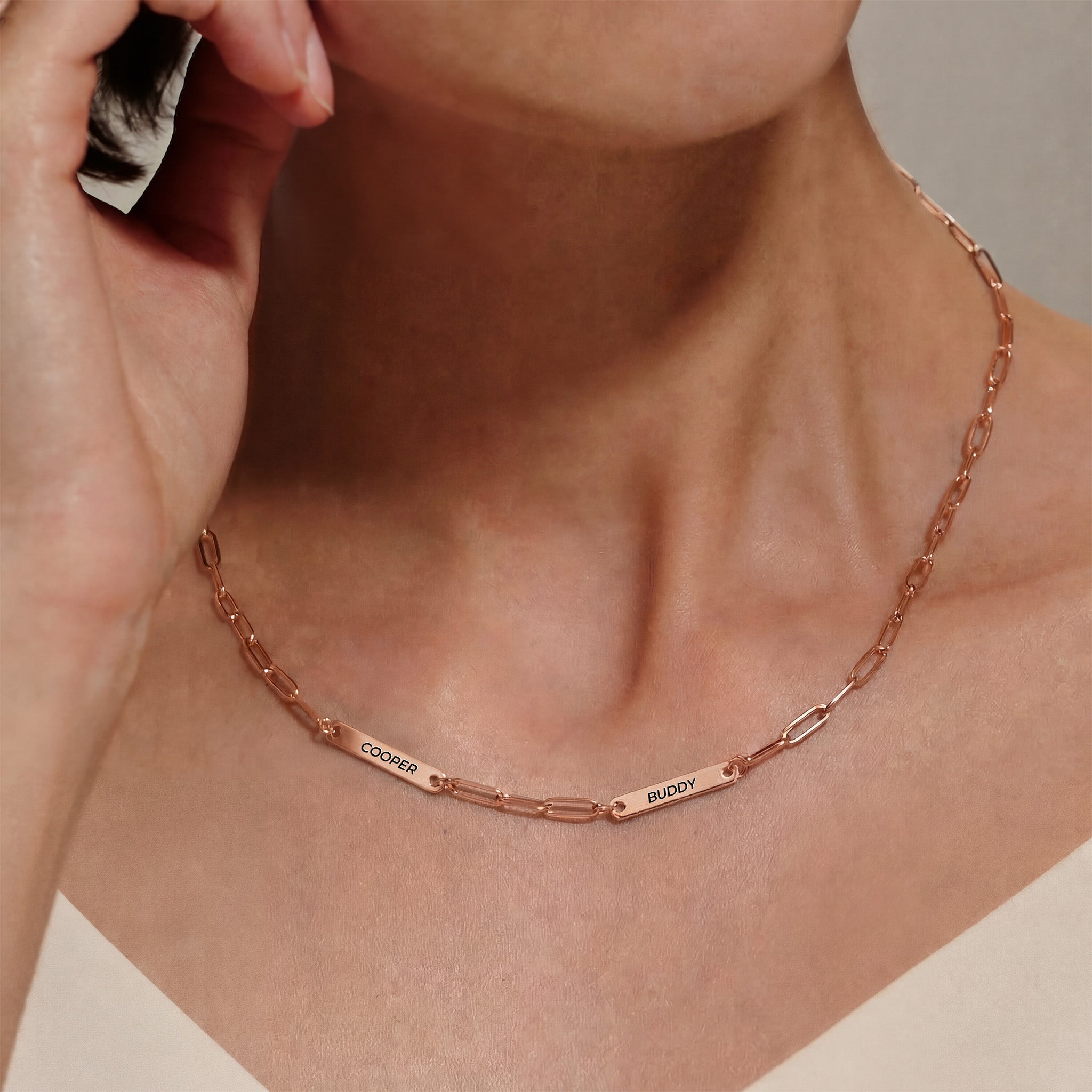 Woman wearing rose gold paperclip chain pet name necklace with two engraved pet name bars