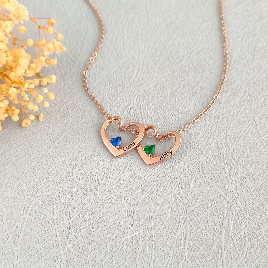 Two 18K rose gold heart pendants with blue and green birthstones and engraved pet names