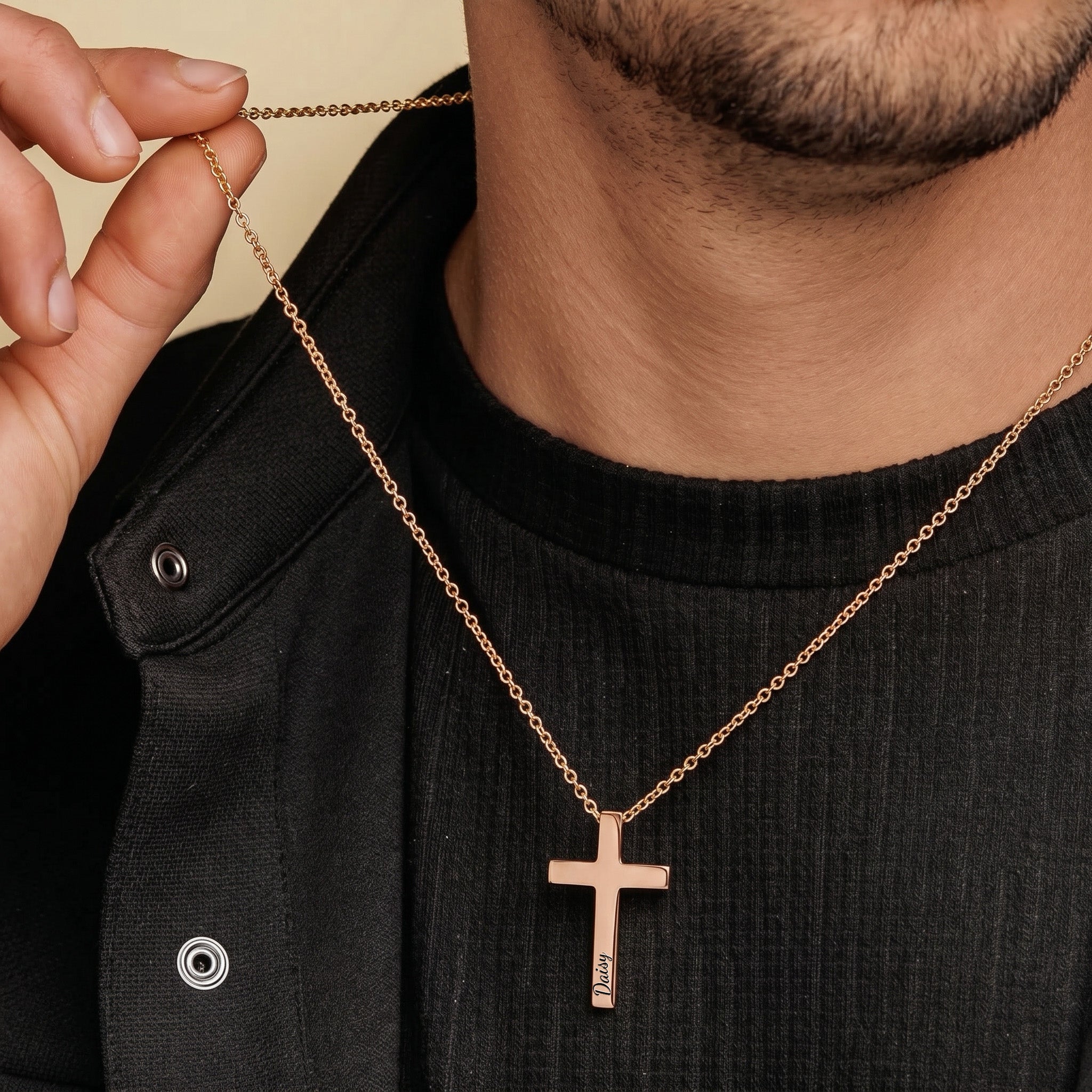 Man wearing rose gold personalized cross necklace over dark outfit