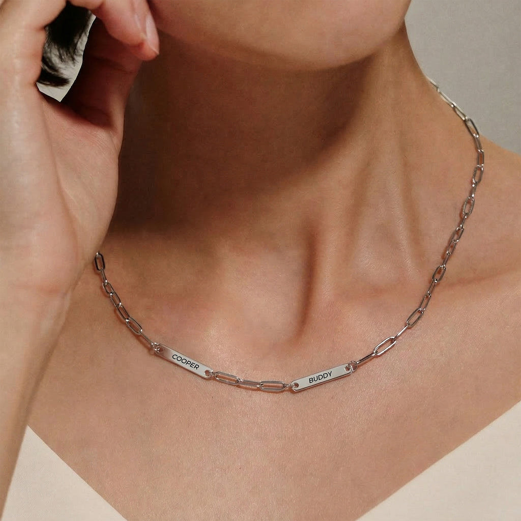 Woman wearing silver paperclip chain pet name necklace with two engraved pet name bars at the collarbone