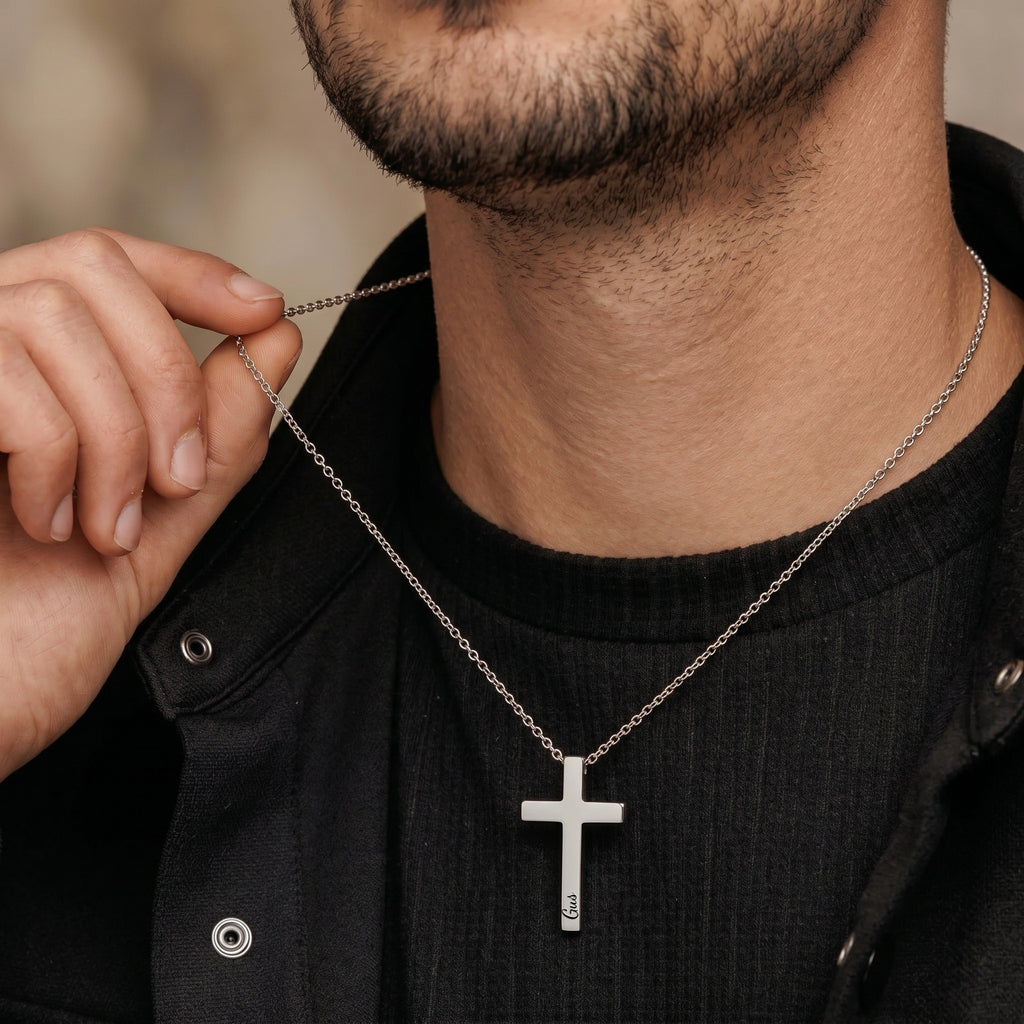 Man wearing silver personalized cross necklace over dark jacket