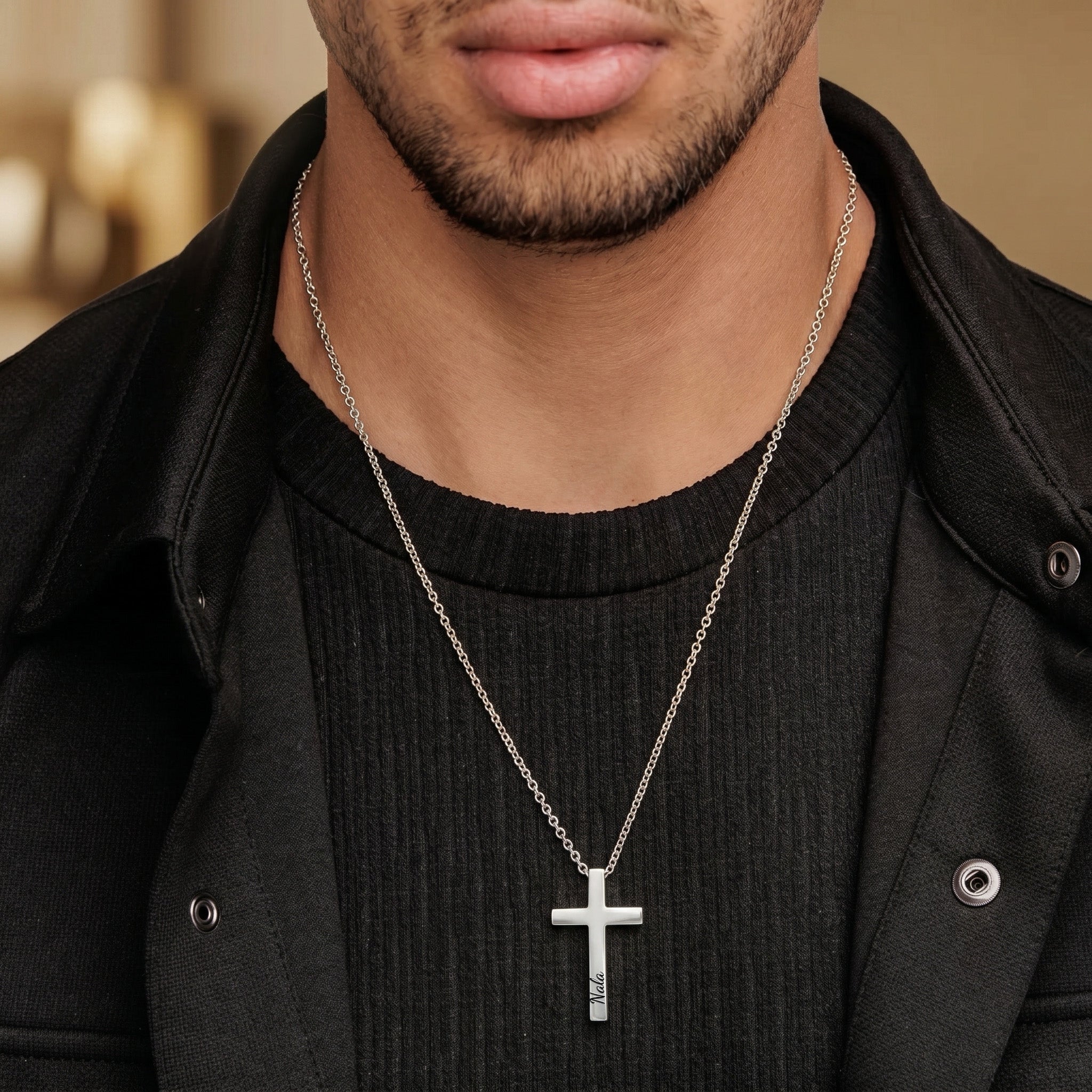 Man wearing silver cross necklace with engraved name, casual style