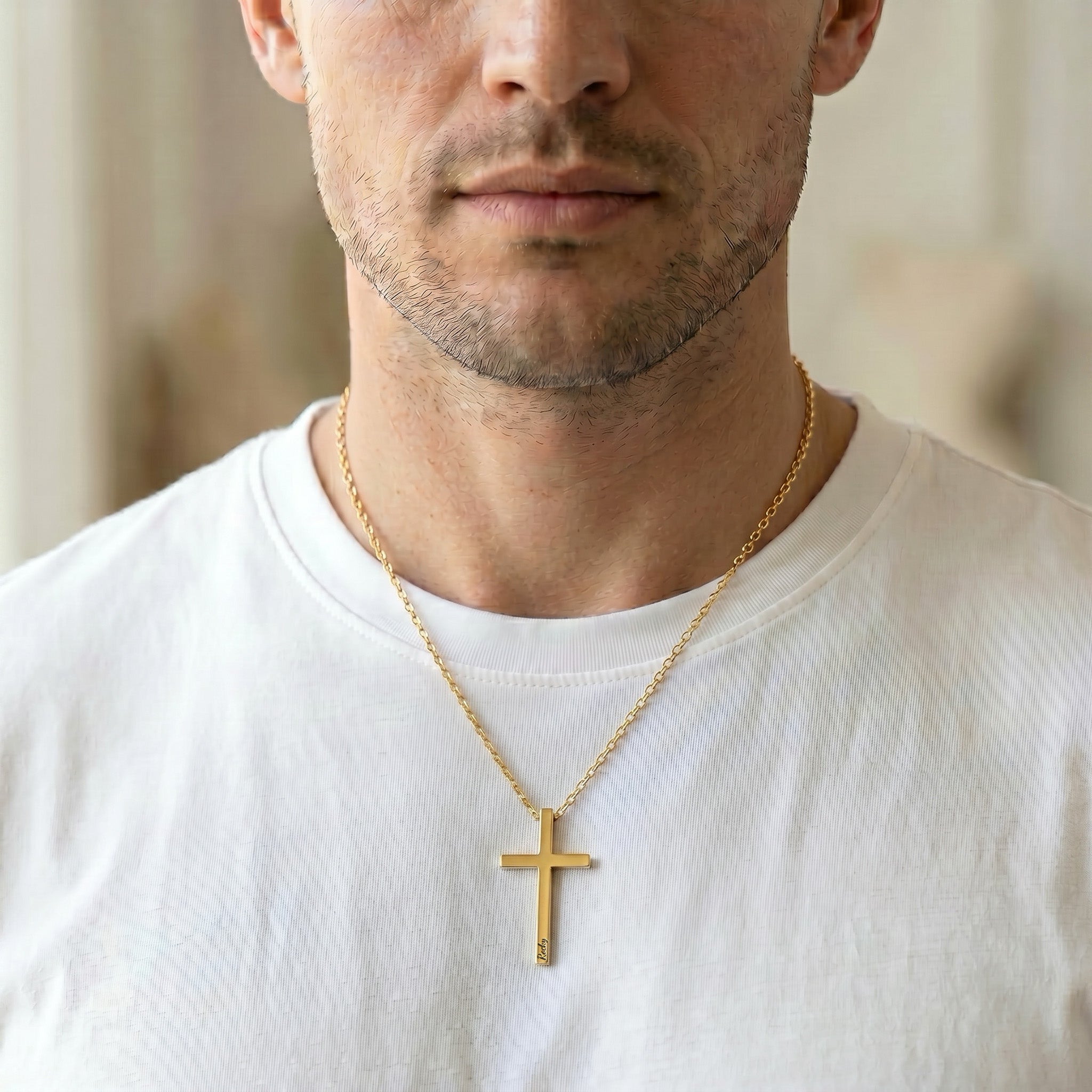 Man wearing 18K gold cross necklace with engraved pet name over white t-shirt