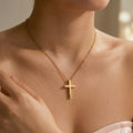 Woman wearing 18K gold cross necklace with engraved pet name, hand touching pendant