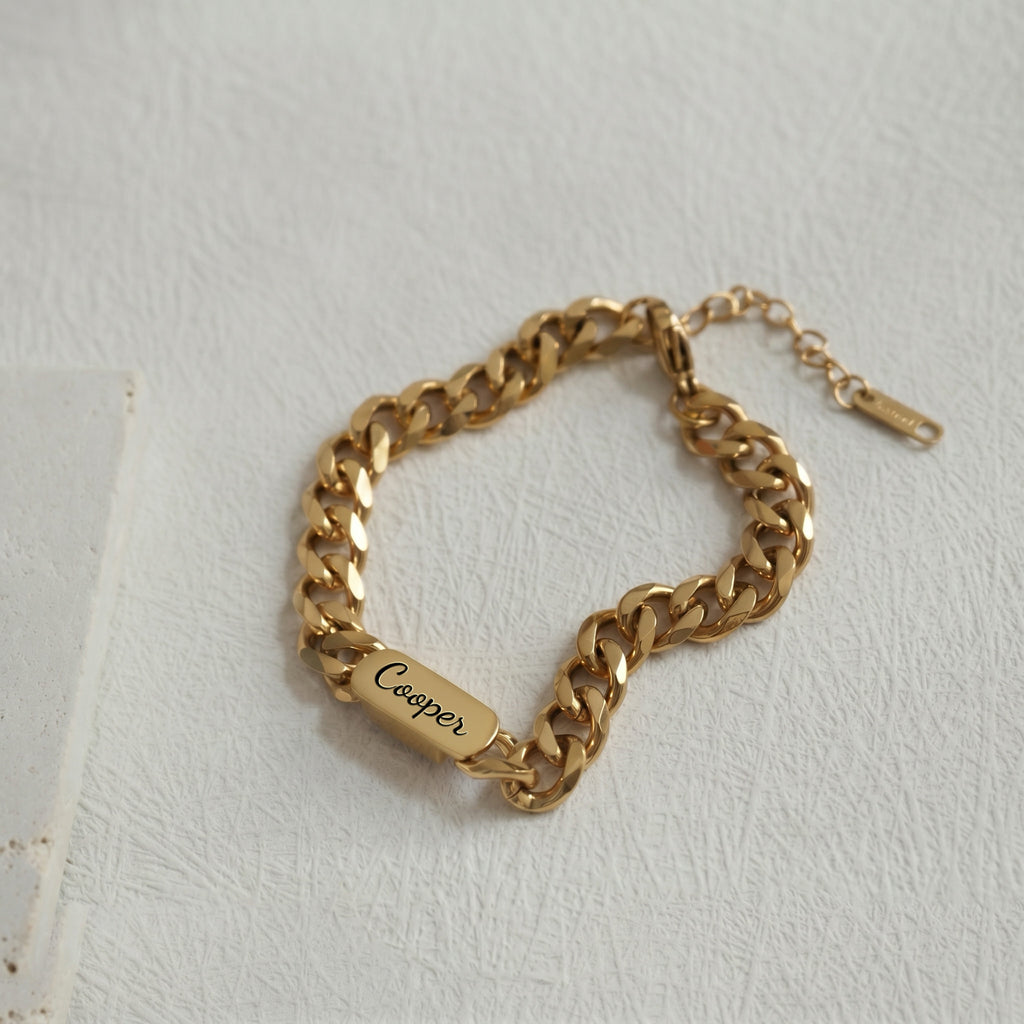 18K gold curb-chain pet name bracelet with an engraved oval nameplate on a neutral surface