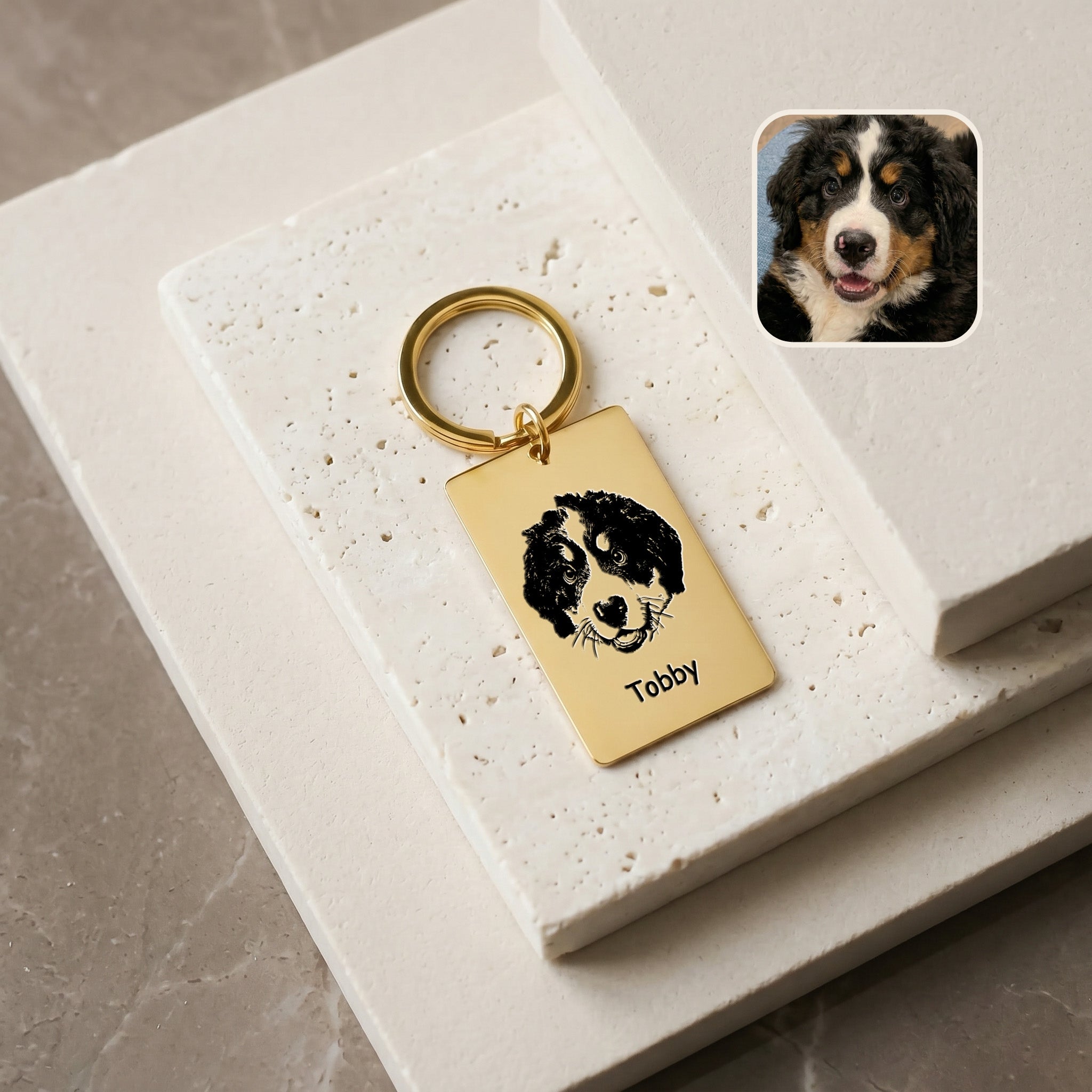 18k gold pet portrait plate keychain on travertine blocks with a Bernese Mountain Dog puppy reference photo inset, hand-drawn portrait and name 'Tobby' engraved