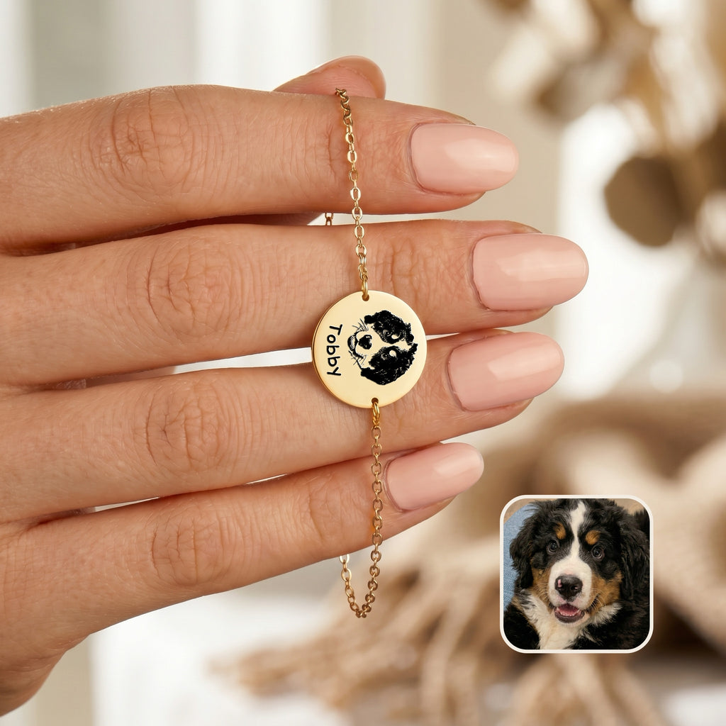 Gold-plated chain bracelet held in hand showing hand-drawn dog portrait and name on disc charm, with inset Bernese Mountain Dog photo