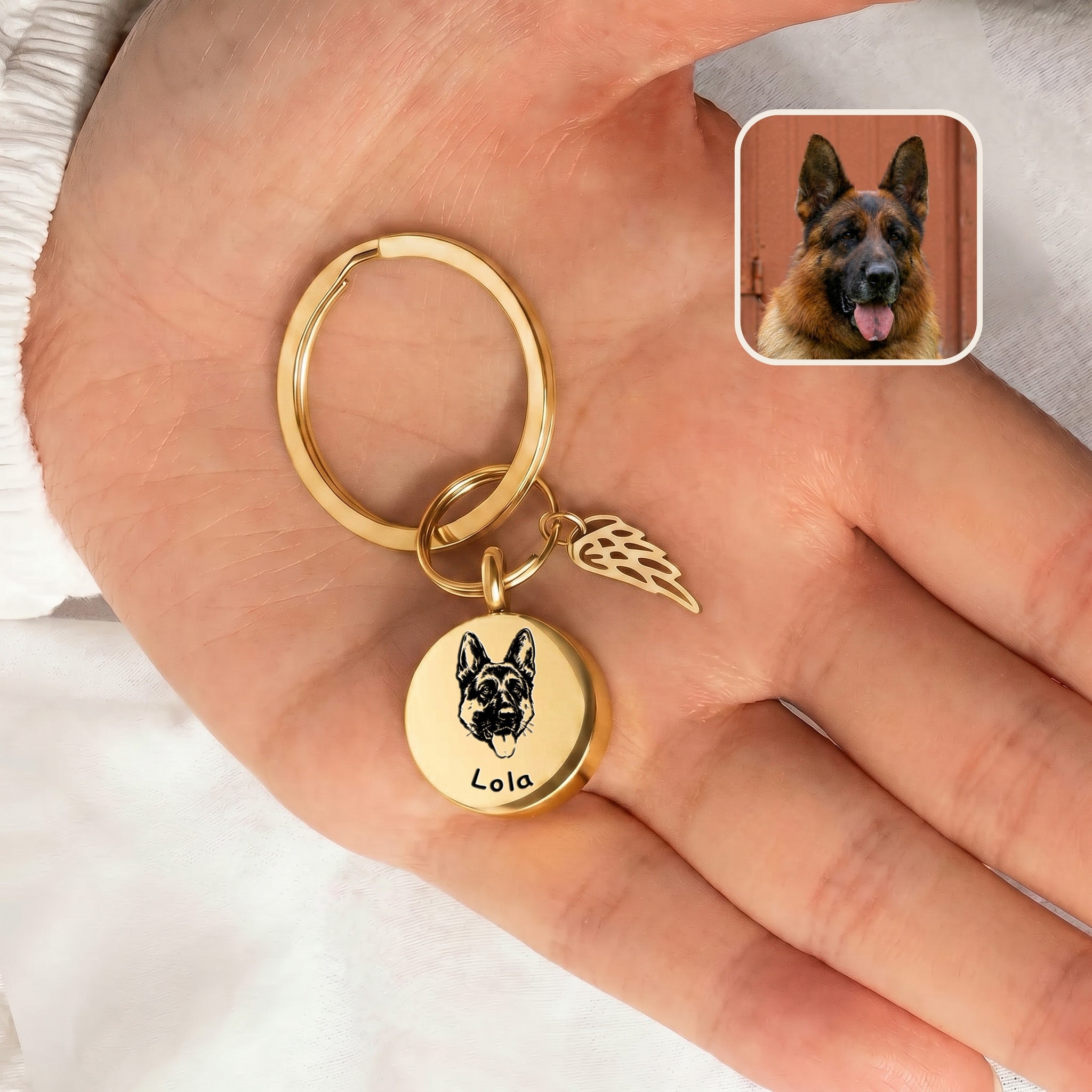 18k gold-plated pet cremation disc keychain with angel-wing memorial charm shown in an open hand beside a reference dog photo inset, scale-only no in-use carry