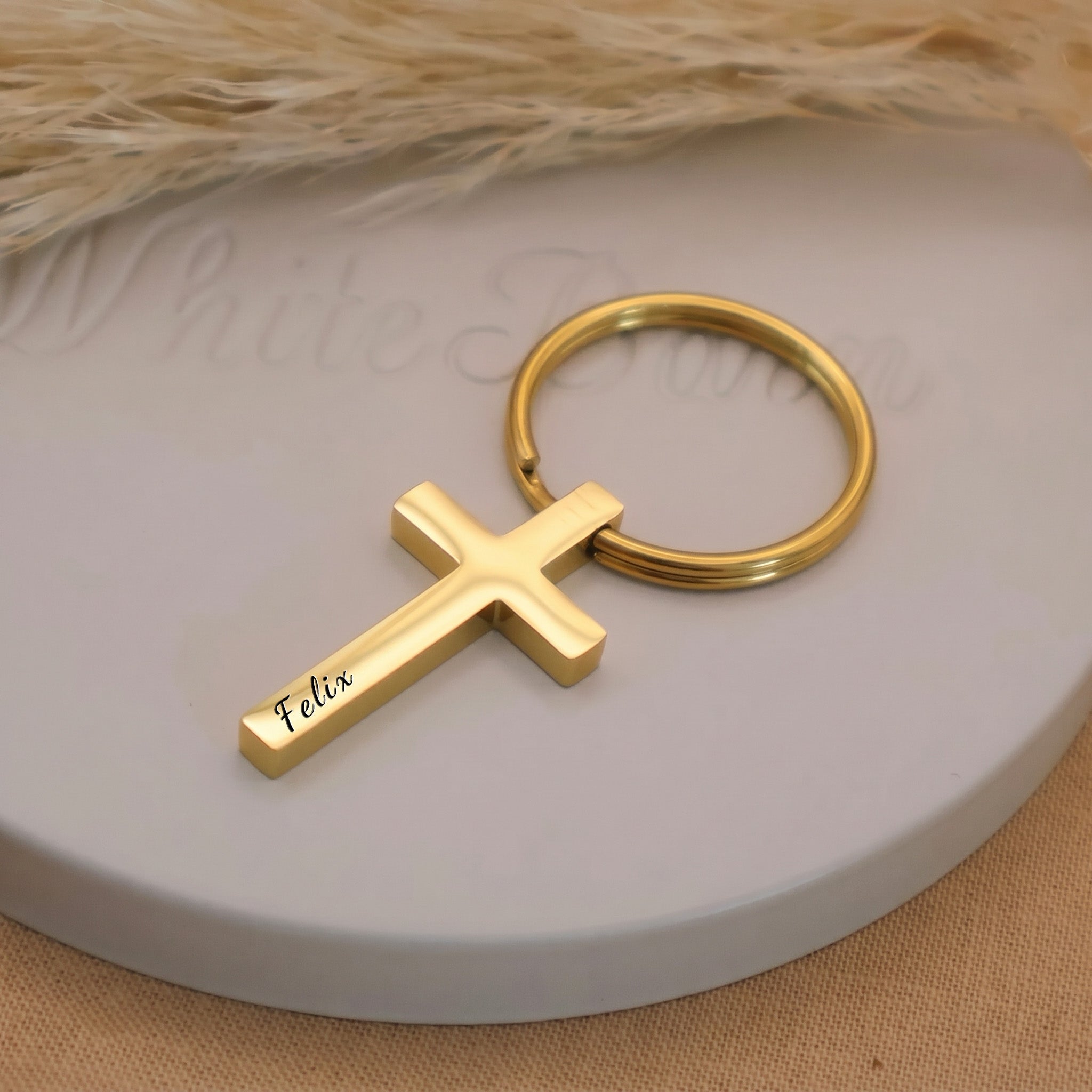 18k yellow gold pet cross keychain close-up — pet name laser-engraved in script on the front face of the 29x17mm cross pendant