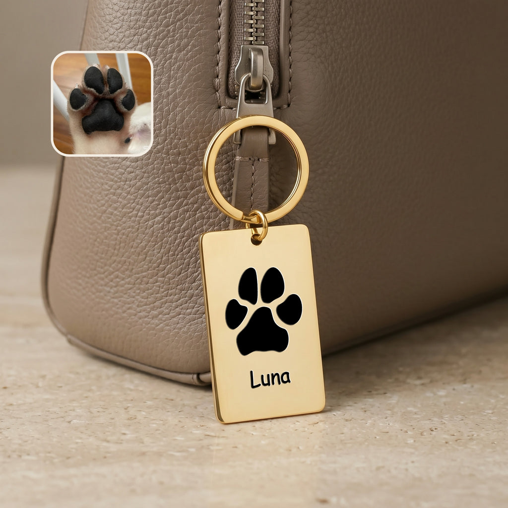 18k gold plate keychain clipped to a taupe handbag, paw print motif and name 'Luna' engraved on the rectangular plate
