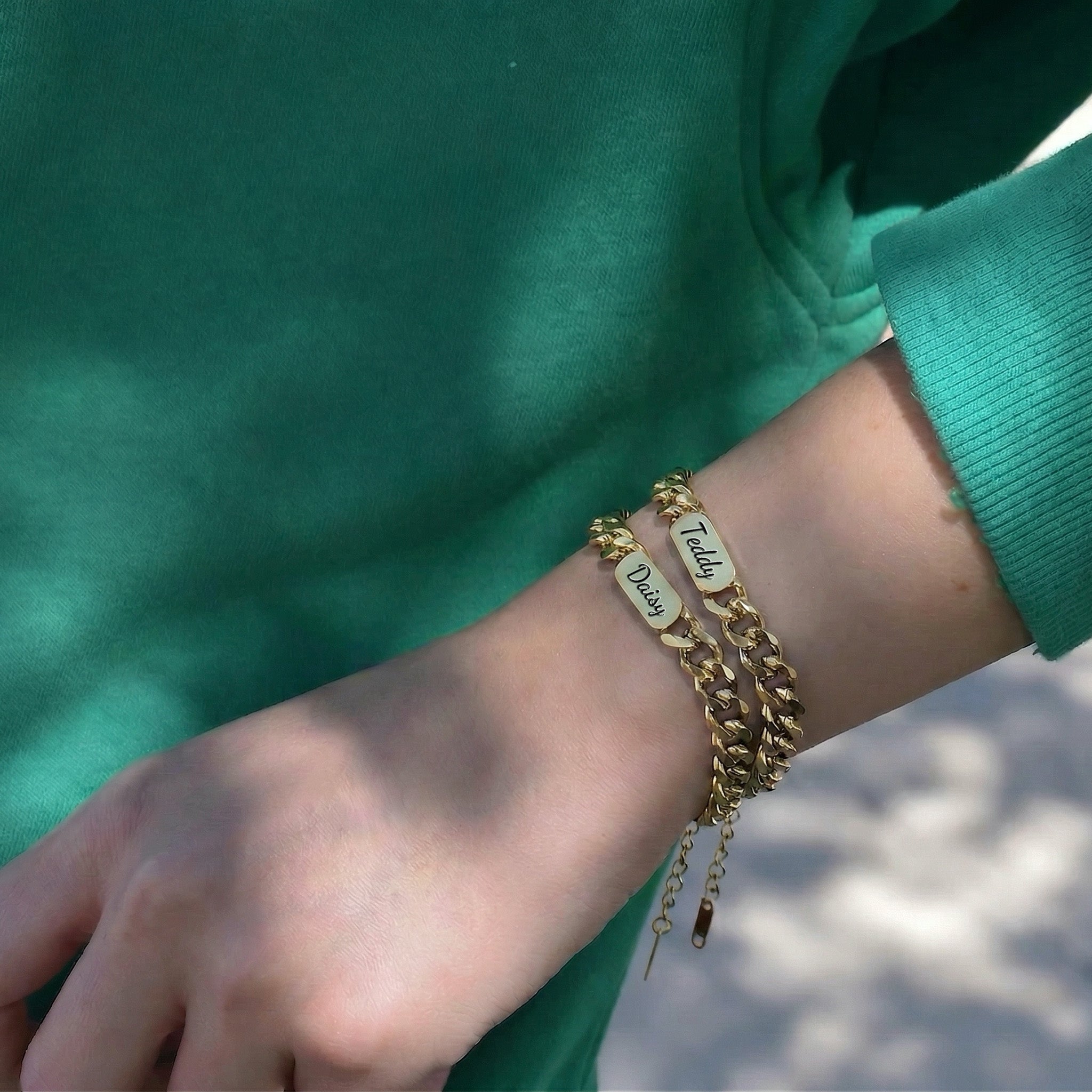 Two 18K gold pet name bracelets stacked on the wrist, each with a script-engraved nameplate