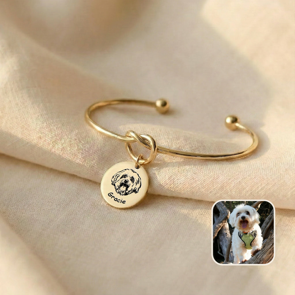 Gold knot cuff bracelet with engraved Maltese dog portrait disc charm on cream linen, with reference photo inset