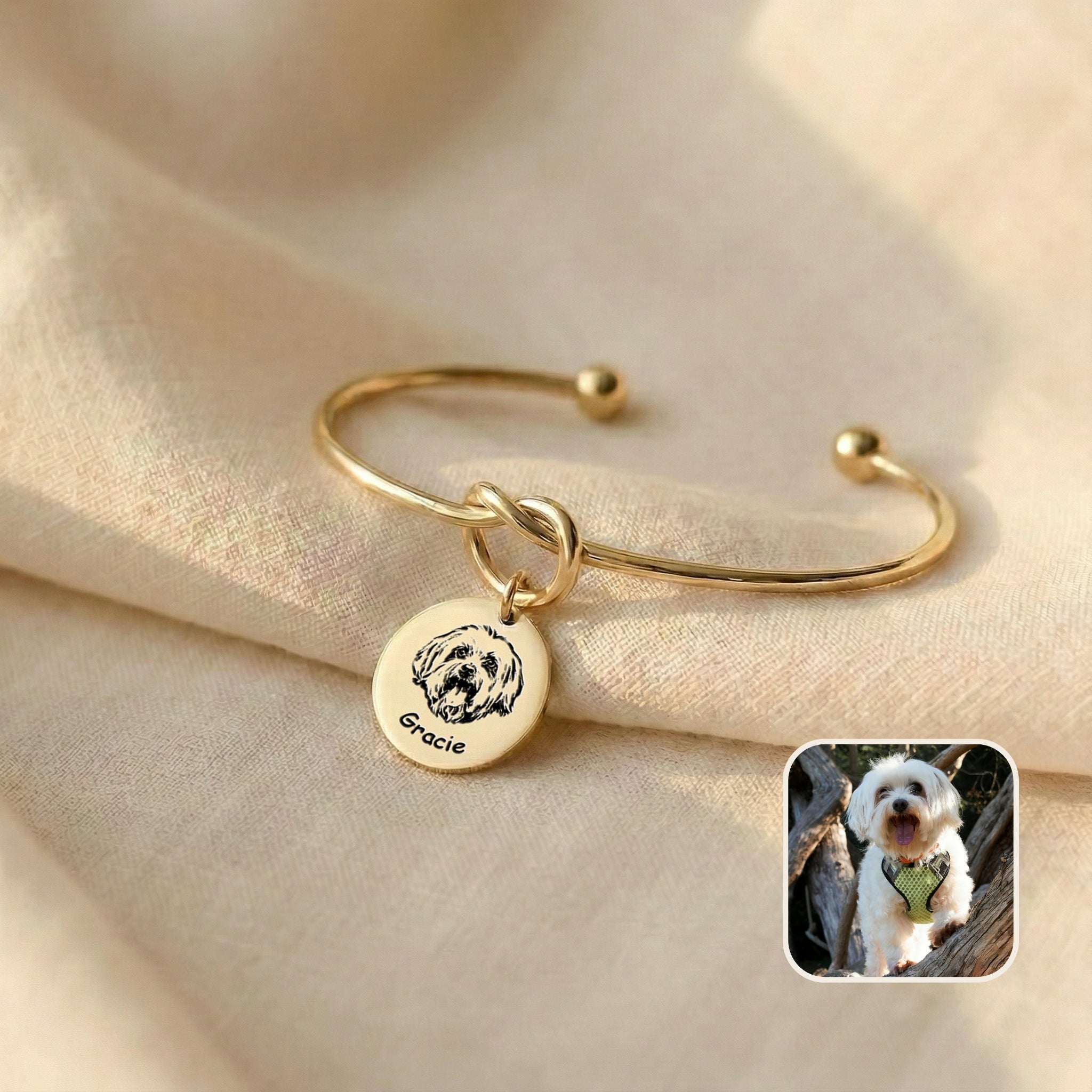 Gold knot cuff bracelet with engraved Maltese dog portrait disc charm on cream linen, with reference photo inset