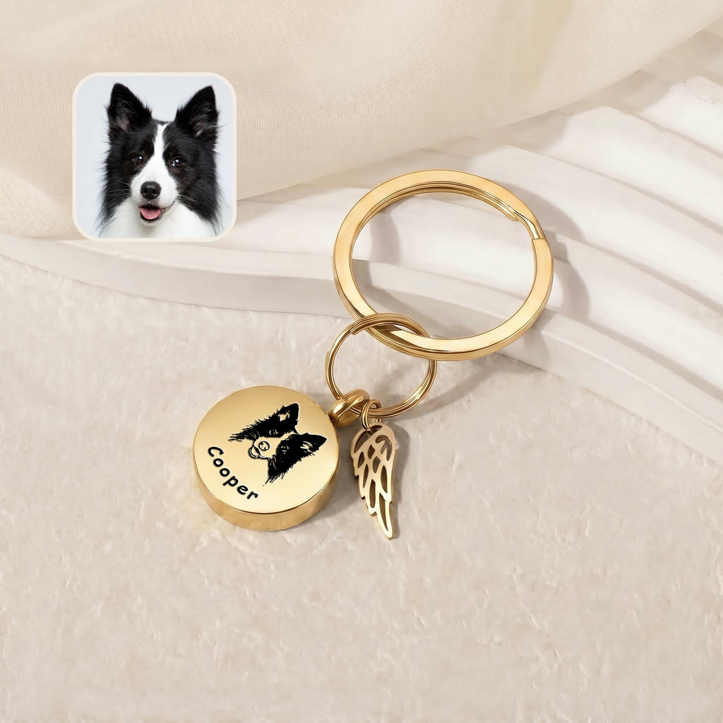 18k gold-plated pet cremation disc keychain &mdash; engraved disc and angel-wing memorial charm on a pale stepped tray beside a black-and-white reference pet photo inset