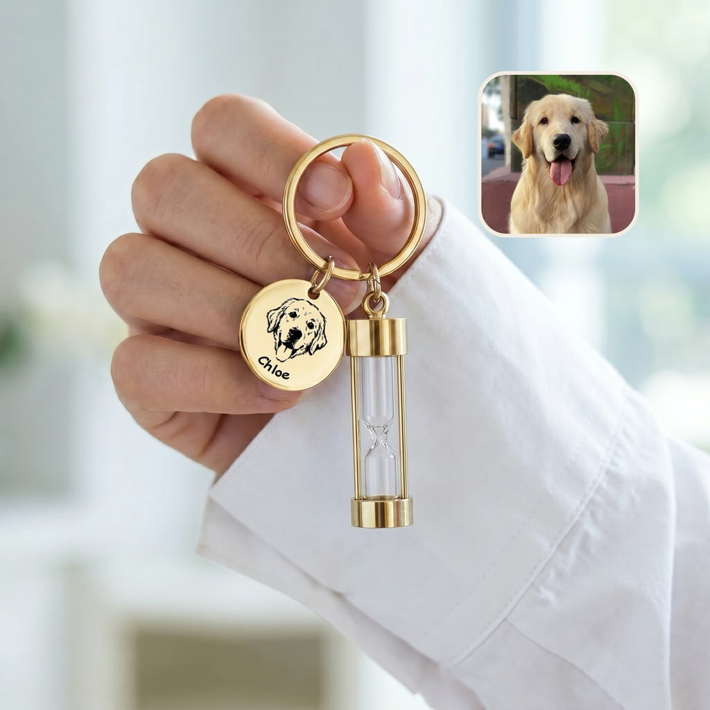 18k gold-plated pet portrait hourglass keychain held against white sleeve with engraved golden retriever portrait disc and glass hourglass urn, with reference photo inset
