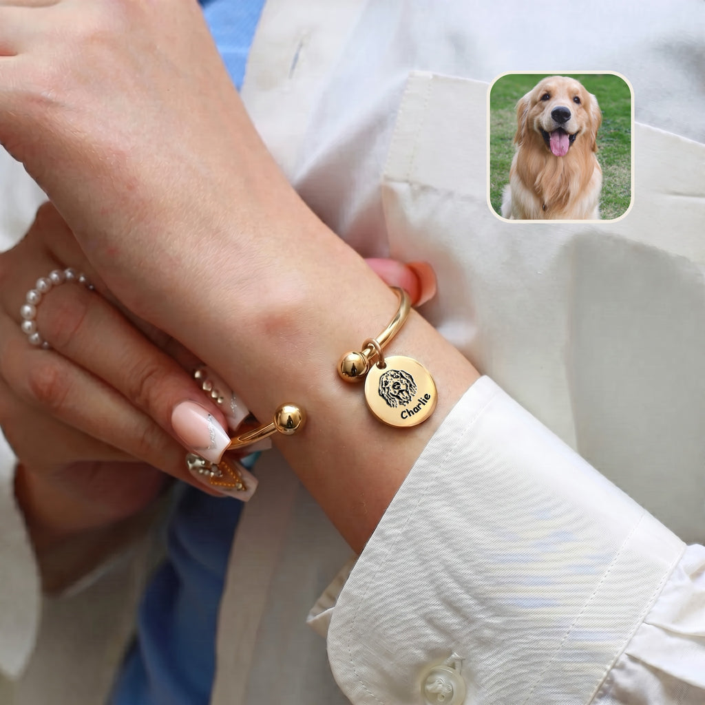 Gold-plated pet photo bracelet worn over a white sleeve, with an inset golden retriever photo