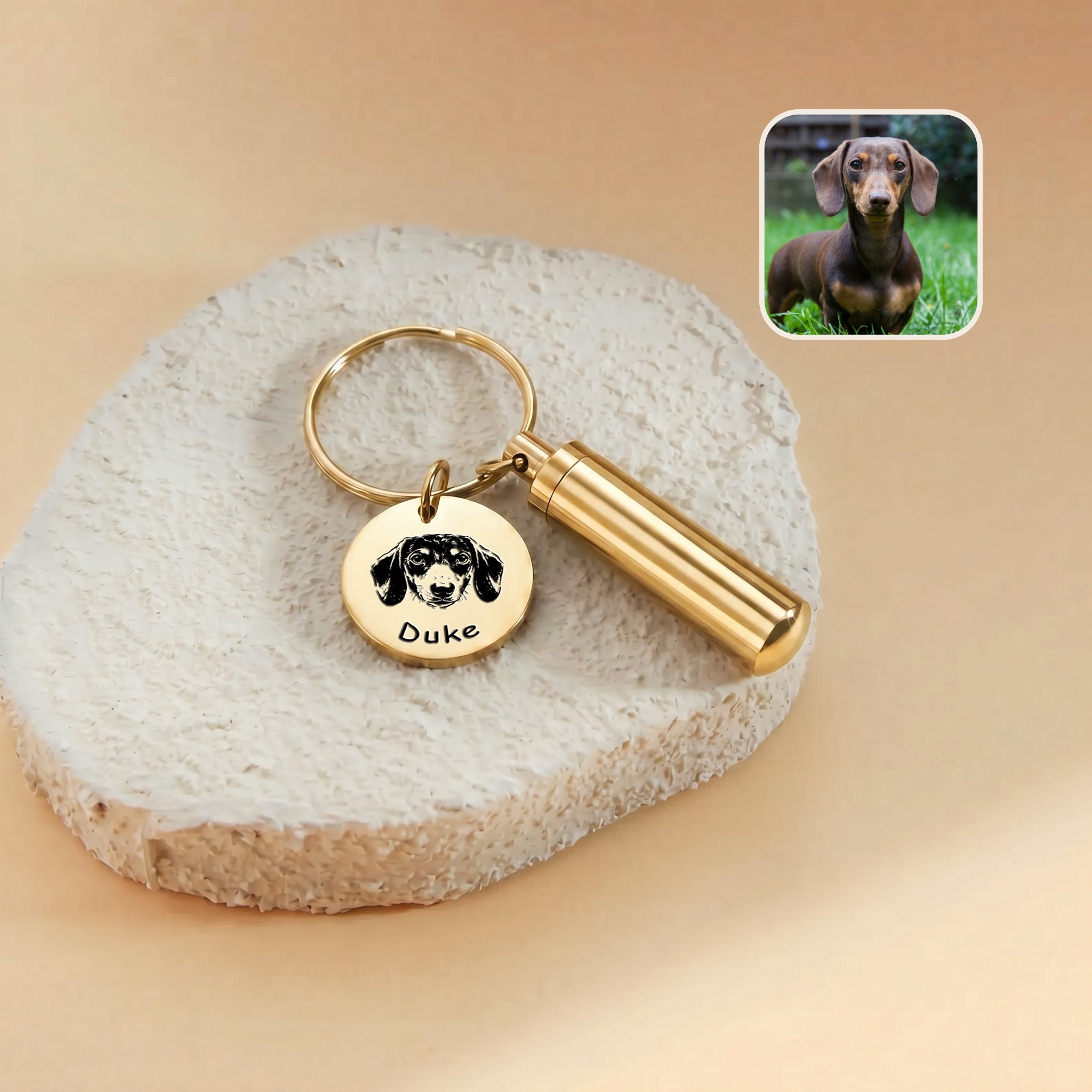 18k gold-plated pet portrait and ashes cylinder keychain close-up &mdash; engraved disc with hand-drawn dachshund portrait and the name Duke beside the cylinder urn, with a reference photo inset