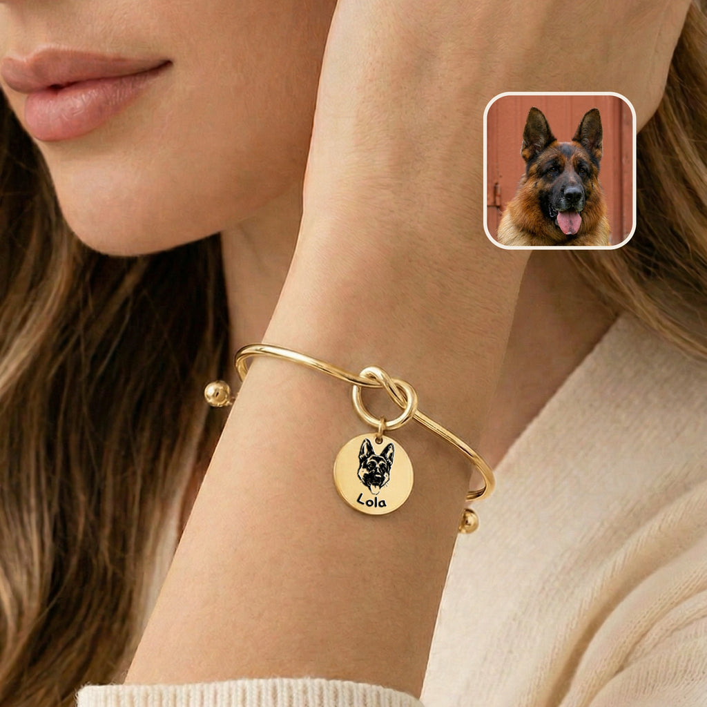 Gold knot cuff bracelet with engraved German shepherd portrait charm worn on a wrist near the face, photo inset