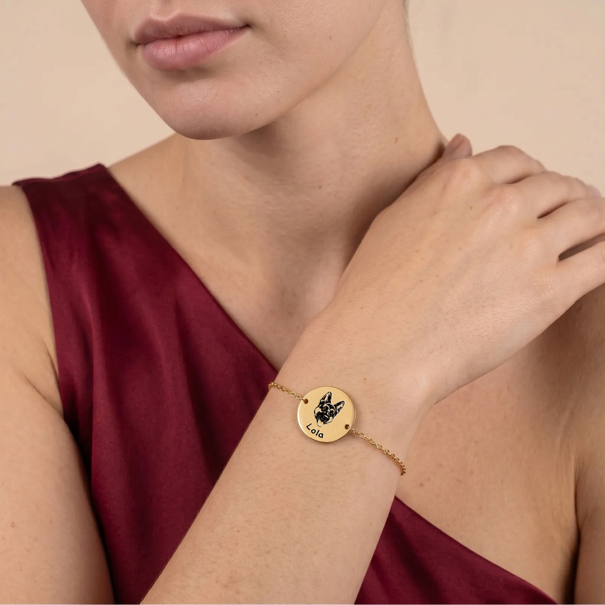 Gold-plated pet portrait chain bracelet worn on a wrist against burgundy fabric, hand-drawn French Bulldog portrait on disc