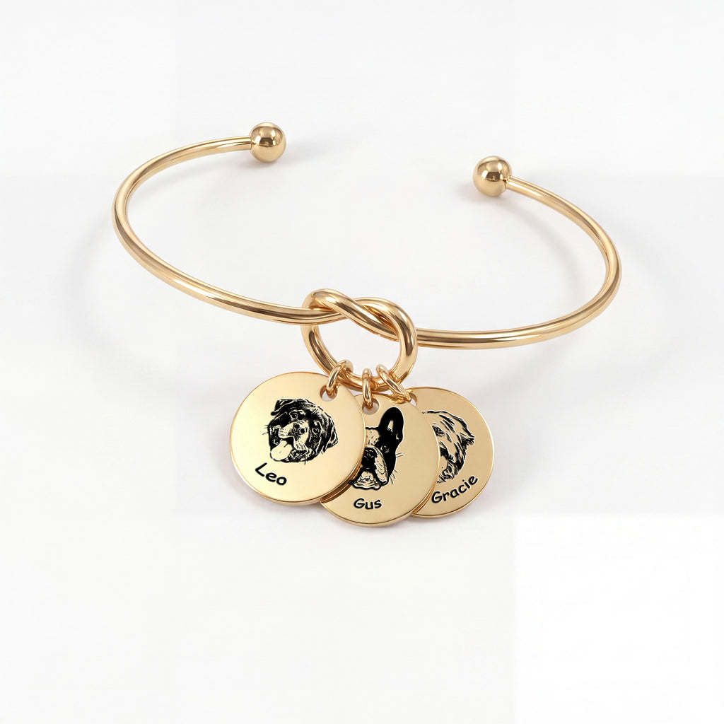 Gold knot cuff bracelet with three engraved pet portrait disc charms on a white background