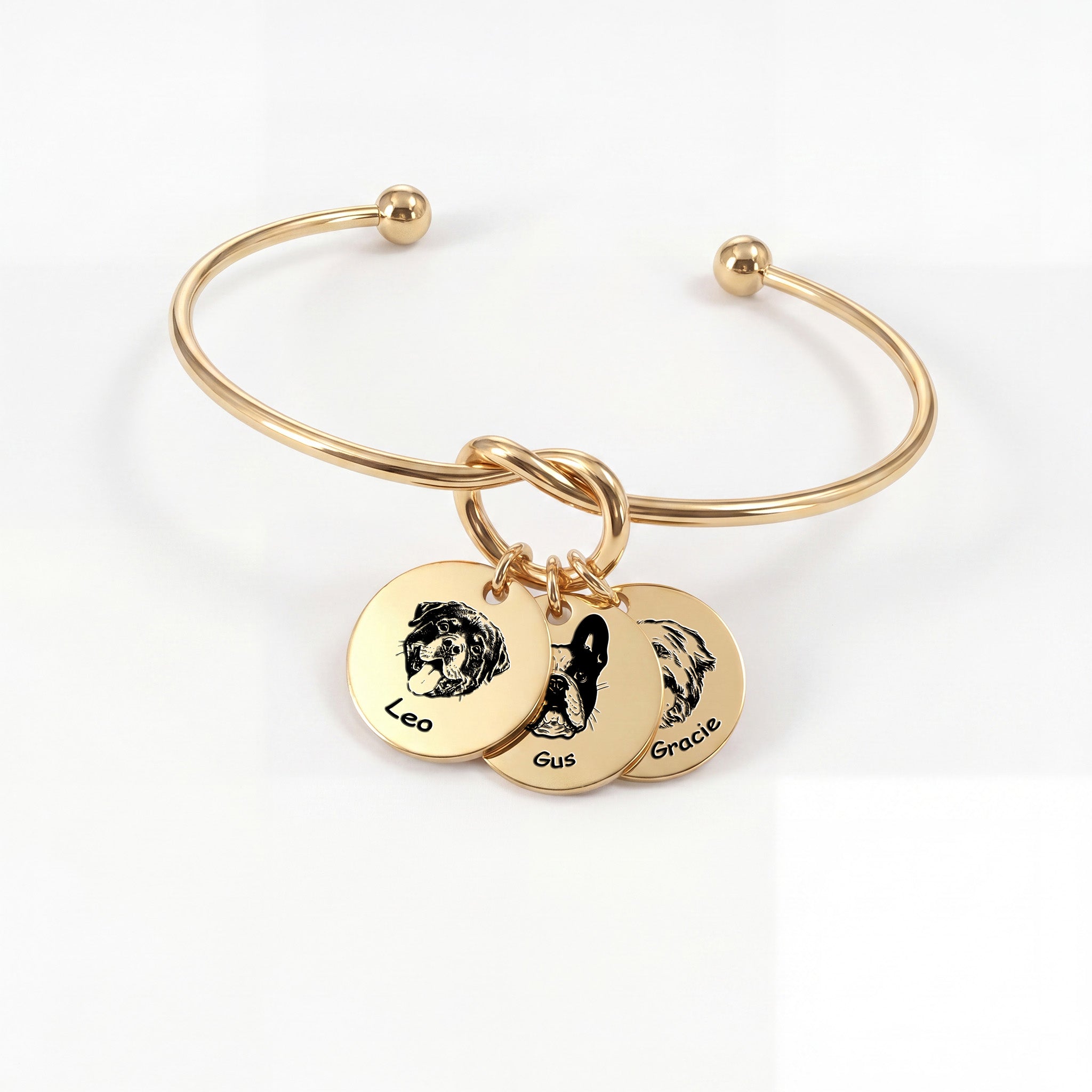 Gold knot cuff bracelet with three engraved pet portrait disc charms on a white background