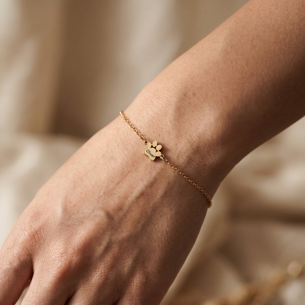 Single gold paw charm engraved with a pet name on an adjustable wrist bracelet