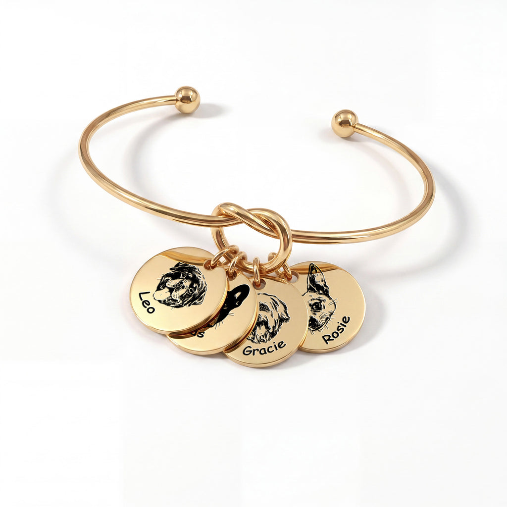 Gold knot cuff bracelet with four engraved pet portrait disc charms on a white background